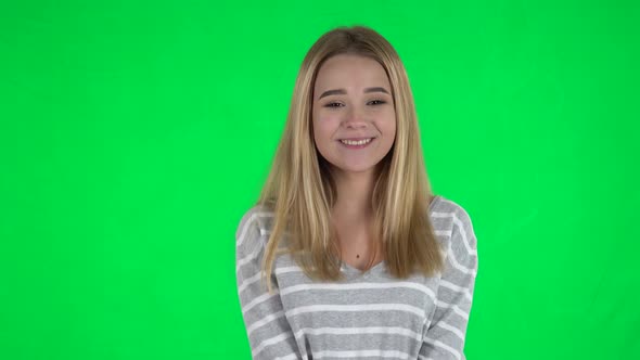 Portrait of Cute Girl with Long Hair Is Clapping Her Hands and Tender Smiling on Green Screen