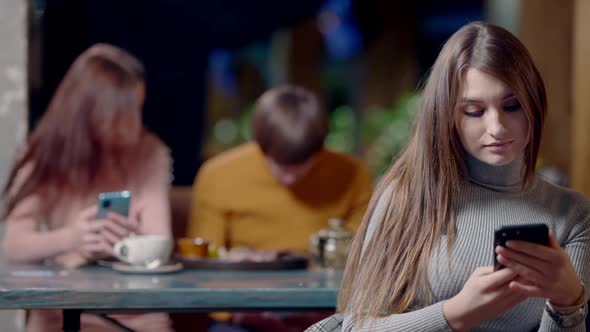 Portrait of Young Slim Caucasian Brunette Woman Messaging on Smartphone and Smiling at Camera with