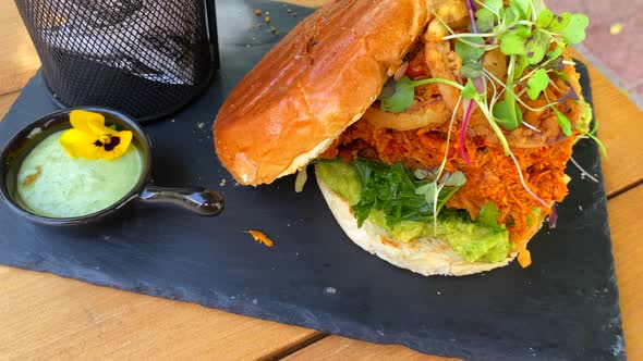 Juicy pulled chicken burger with onion rings, avocado, crispy kale, brioche bun and sweet potato fre