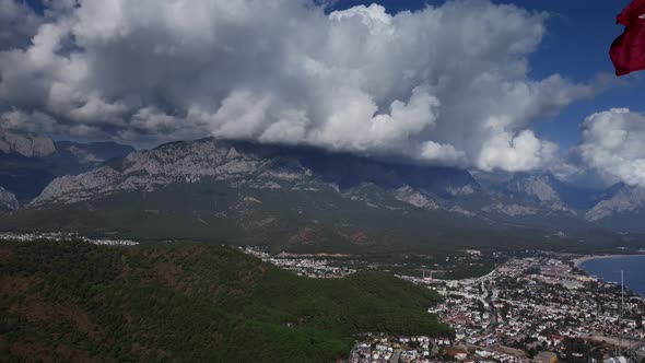 Aerial View of Green Mountains and Coastal Town Next to Cliff with Tower and Turkish Flag in Summer