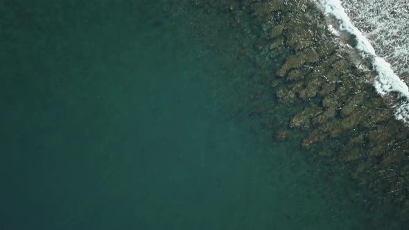 drone shot in bird's eye view, going forward above the reef and the waves in Mauritius island