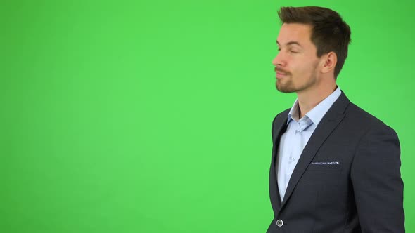 A Young Handsome Businessman Points at Bullet-point Text, Smiles and Nods - Green Screen Studio