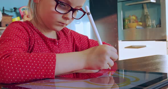 Little Girl Drawing on Tablet at Home. Child Drawing on Tablet Device in Kitchen on Distance