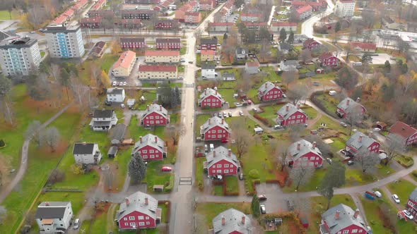 Drone footage flying over some beautiful red houses surrounded with green grass in a small town in S