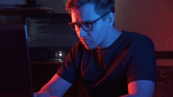 Portrait of a Man in a Dark Room at a Computer Wearing Glasses
