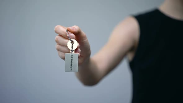 Happiness Word on Keychain in Female Hand, Independent Achievement of Success