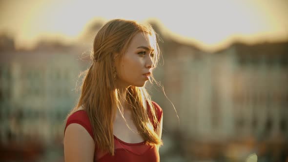 A Young Inspired Woman in Red Dress Standing on the Roof on Bright Sunset