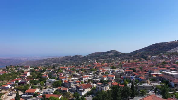 Town with Red Roofed Buildings and Green Trees By Hill