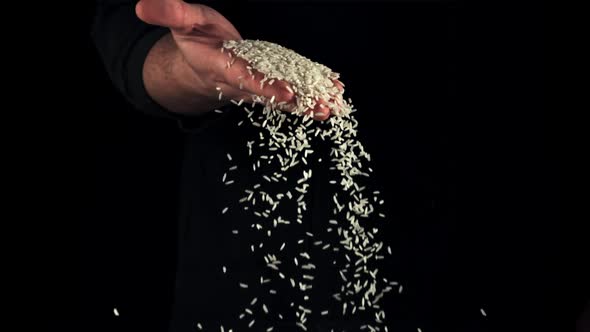 A Handful of Uncooked Rice Falls From a Man's Hand