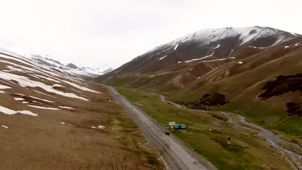 Aerial of highway in prairie with snowy summits of mountain in the background