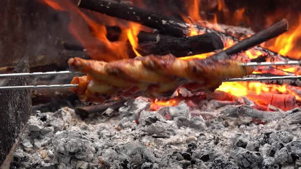 Mouthwatering Chicken Wings on the Skewers Are Flipped Above the Open Fire