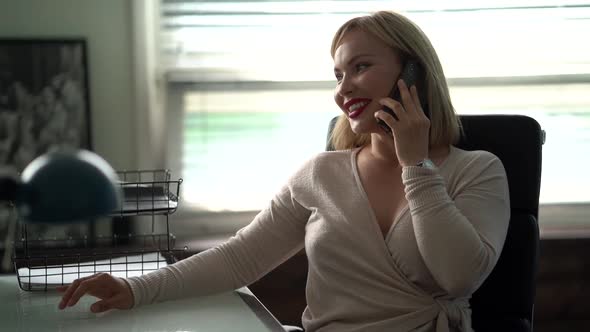 A Portrait in Profile of a Middle-aged Woman with Blond Hair, Sitting at an Office Desk on a Chair