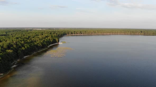 Aerial View of a Lake During a Summer Evening With Dense Forest in Background