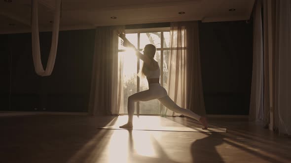 Slow Motion Young Woman is Doing Yoga in a White Room Filled with Light the Girl Performs Yoga