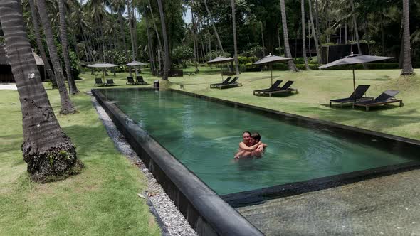 A Panning Shot of a Sexy Happy Caucasian White Couple Embracing in Swimming Pool Vacation