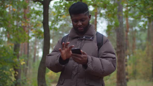 Black Male Traveler Browsing Phone During Hiking