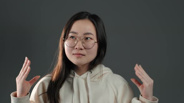 Cute Asian Woman in Glasses Showing Bla-bla-bla Gesture with Hands, Rolling Eyes