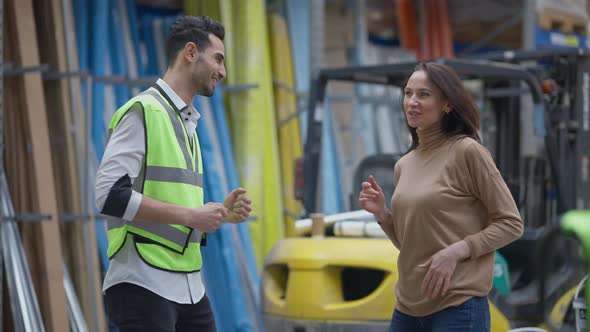 Satisfied Cheerful Middle Eastern Man in Uniform and Caucasian Woman Dancing in Warehouse Indoors