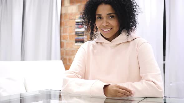 Smiling AfroAmerican Woman Looking at Camera Sitting in Loft Office