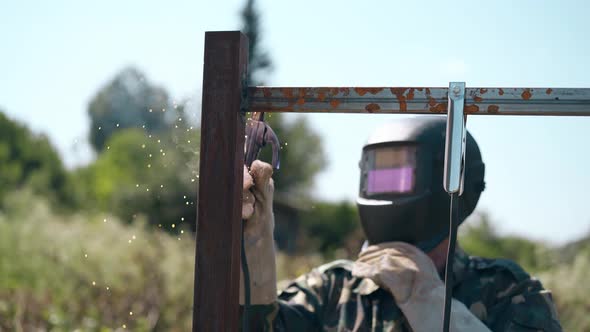 Welder in Mask Fixes Parts of Future Fence Against Clear Sky