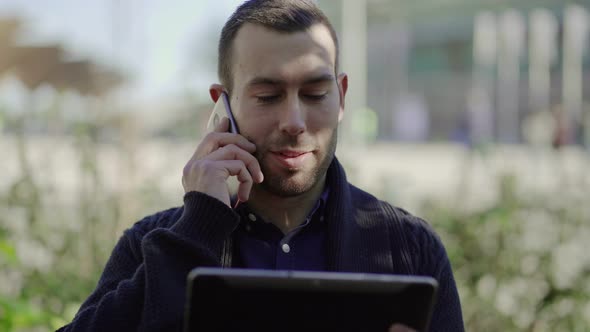 Handsome Man Holding Tablet and Talking on Smartphone