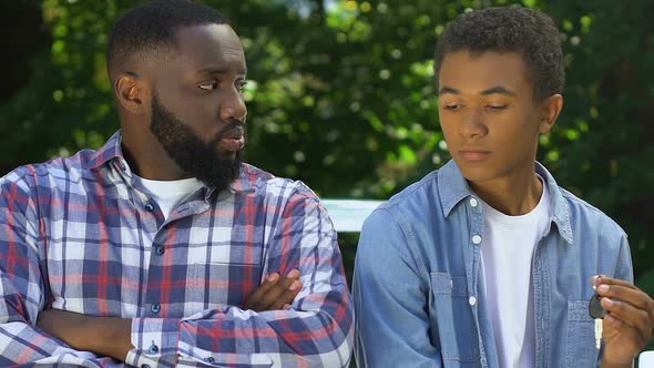 Unhappy Afro-American Father Taking Car Keys From Son Looking Guilty, Punishment