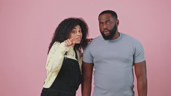 African American Woman Showing Something to Her Boyfriend Pointing at Camera Frowning Faces and