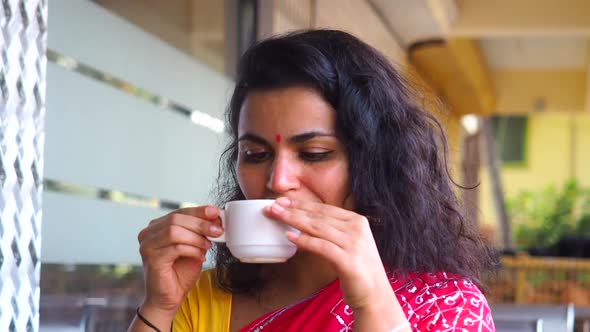 Indian Woman Drinking Masala Tea with Milk and Spices She Wearing Gold Earrings and Bindi Tika on