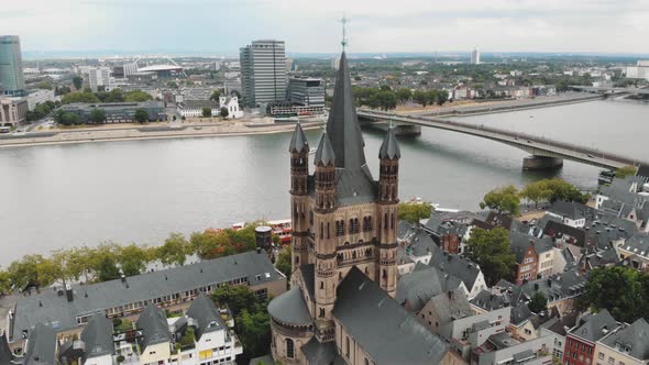 Aerial drone footage of Cologne Cathedral along the shore of the Rhine River in Germany.