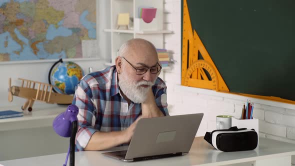 Smiling Senior Man Old Teacher Having Video Call on Laptop, Happy Elderly Male Sit in Class Using