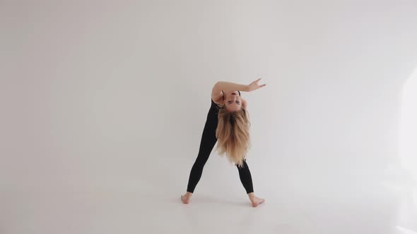 Flexible Young Girl Barefoot is Engaged in Stretching with Elements of Classical Dance in the Studio