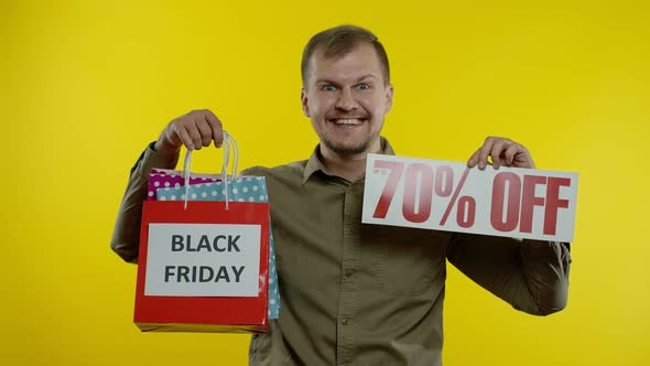 Man Showing Up To 70 Percent Off Inscription and Shopping Bags, Looking Satisfied with Low Prices