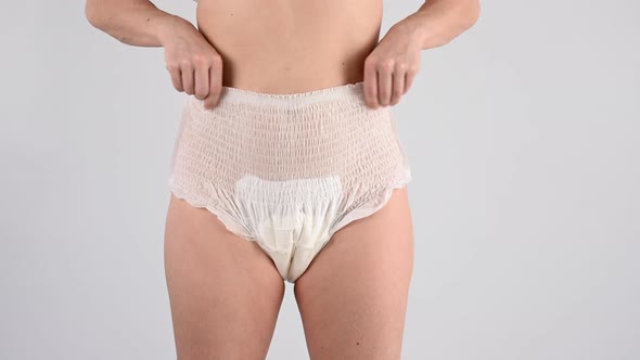 A Faceless Woman Adjusts the Elastic of Adult Diapers