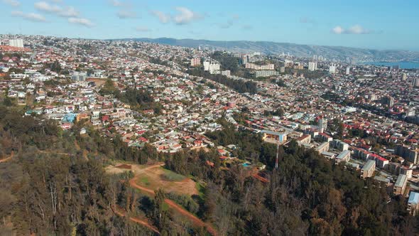 Aerial pan right of Viña del Mar city buildings panormic view from hill, mountains and sea in backgr