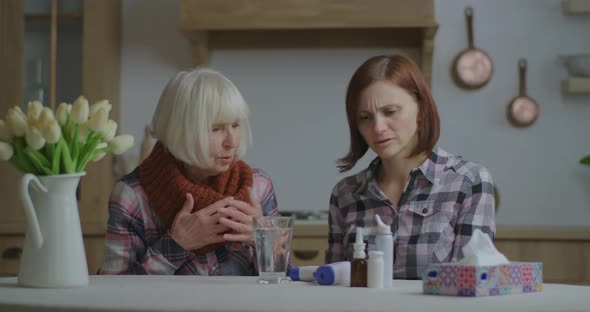 Young Adult Woman Measures Temperature To Her Sick Senior Mother Staying at Home. Female Helping Her