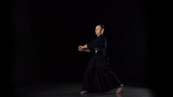 Kendo Warrior Practicing Martial Art with the Katana Sword on Black Background