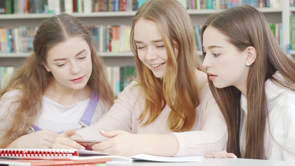 Teen Friends Laughing at the Library While Using Smart Phone