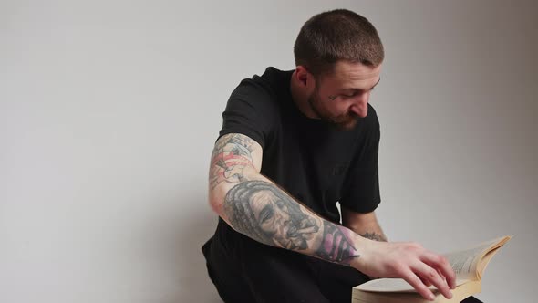 Young Bearded Caucasian Tattooed Man Guy Reading and Flipping the Pages of His Favorite Book Over