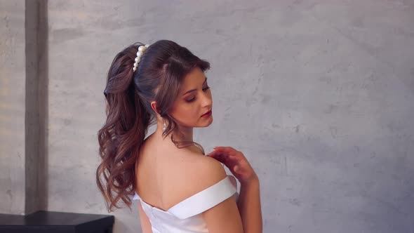 A Girl in a White Dress Poses Coquettishly with Her Back Turned