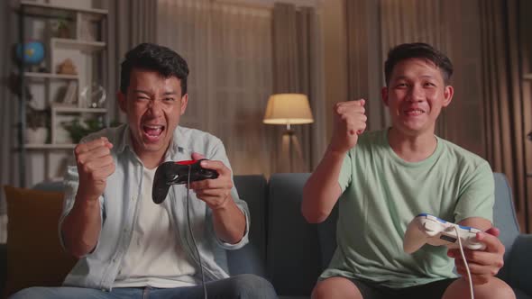 Asian Friends Playing Video Games And Celebrating Victory At Home