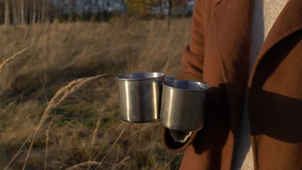 woman hold mugs of tea in mountains Sudetes in November in sunset