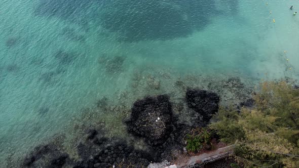 Giant rocks sticking out of turquoise ocean water, aerial top down