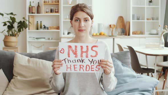 Woman Holding Poster with «NHS thank you heroes» Sign and Posing for Camera