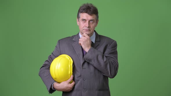 Mature Handsome Businessman Against Green Background