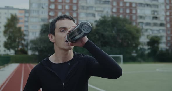 Crop View of Man Athlete Drinking Water From Bottle and Looking Ahead