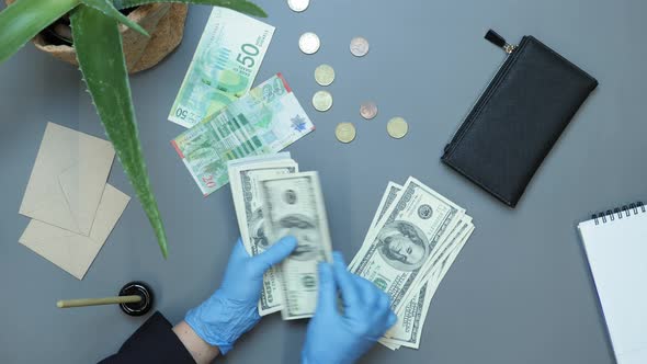 Unrecognizable woman hands in protective gloves with pile of money, counting US dollars bills