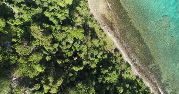 Aerial footage of ocean and land on an island in Tonga. Green lands and blue water