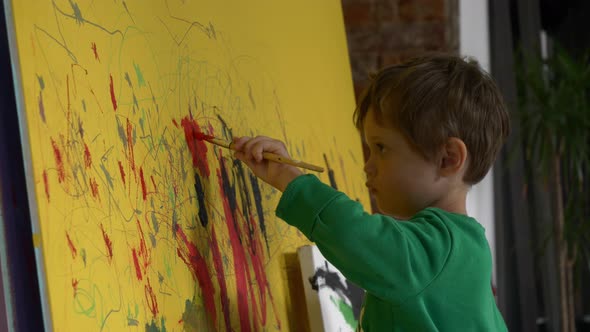 toddler boy is painting on the wall during quarantine