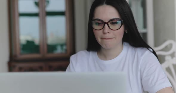 Thoughtful Student in Glasses Working with Laptop and Frazzles Head at Table