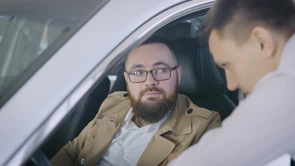 an Adult Man Sits in the Salon of a New Car in a Dealership